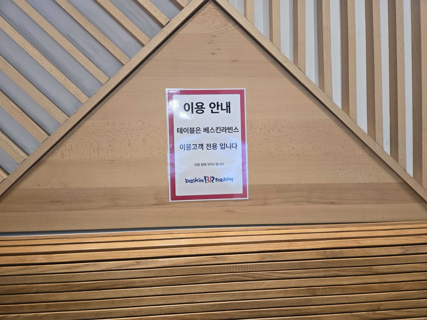 Table notice sign at Baskin-Robbins Wirye Traders on a wood-slat wall