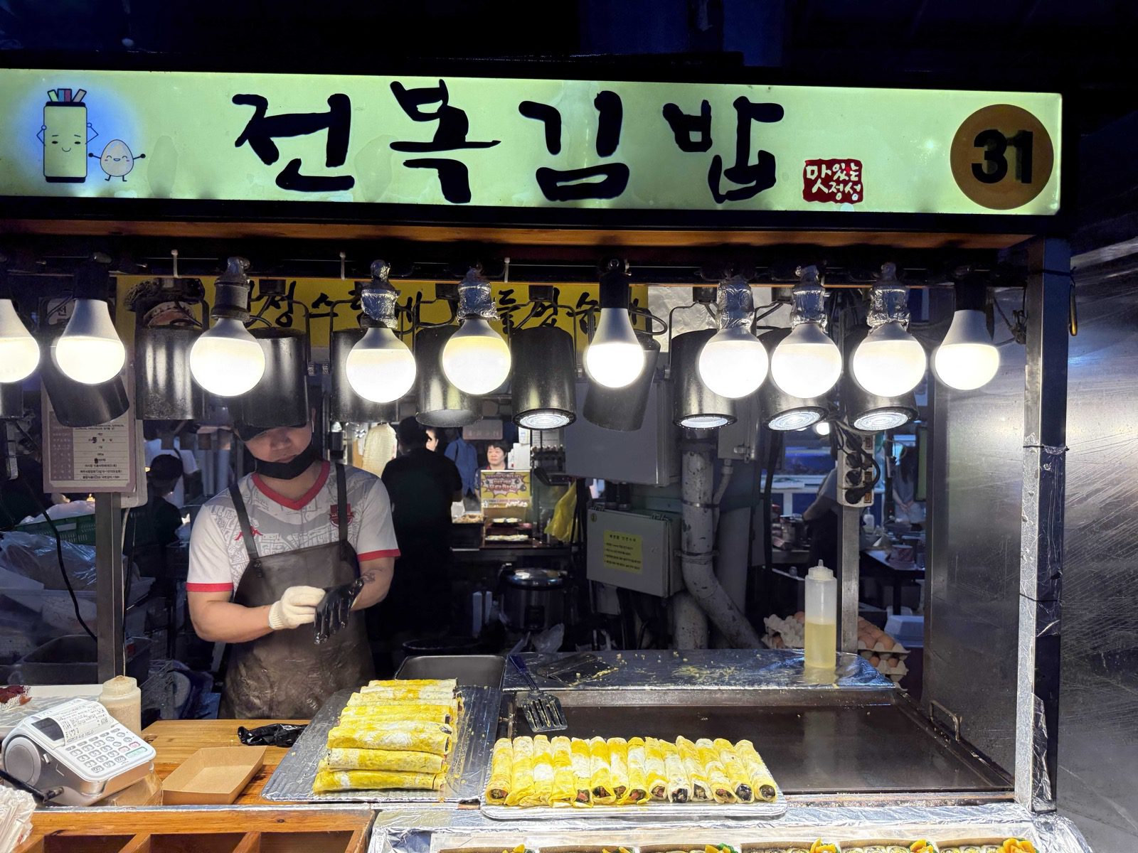 Abalone gimbap stall under bulb lights at Jeju Dongmun Market