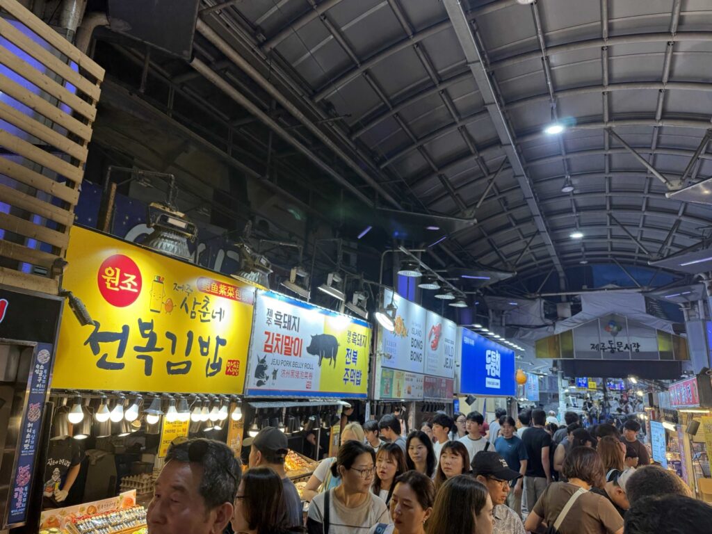 Jeju Dongmun Market night market crowd and glowing stall signs