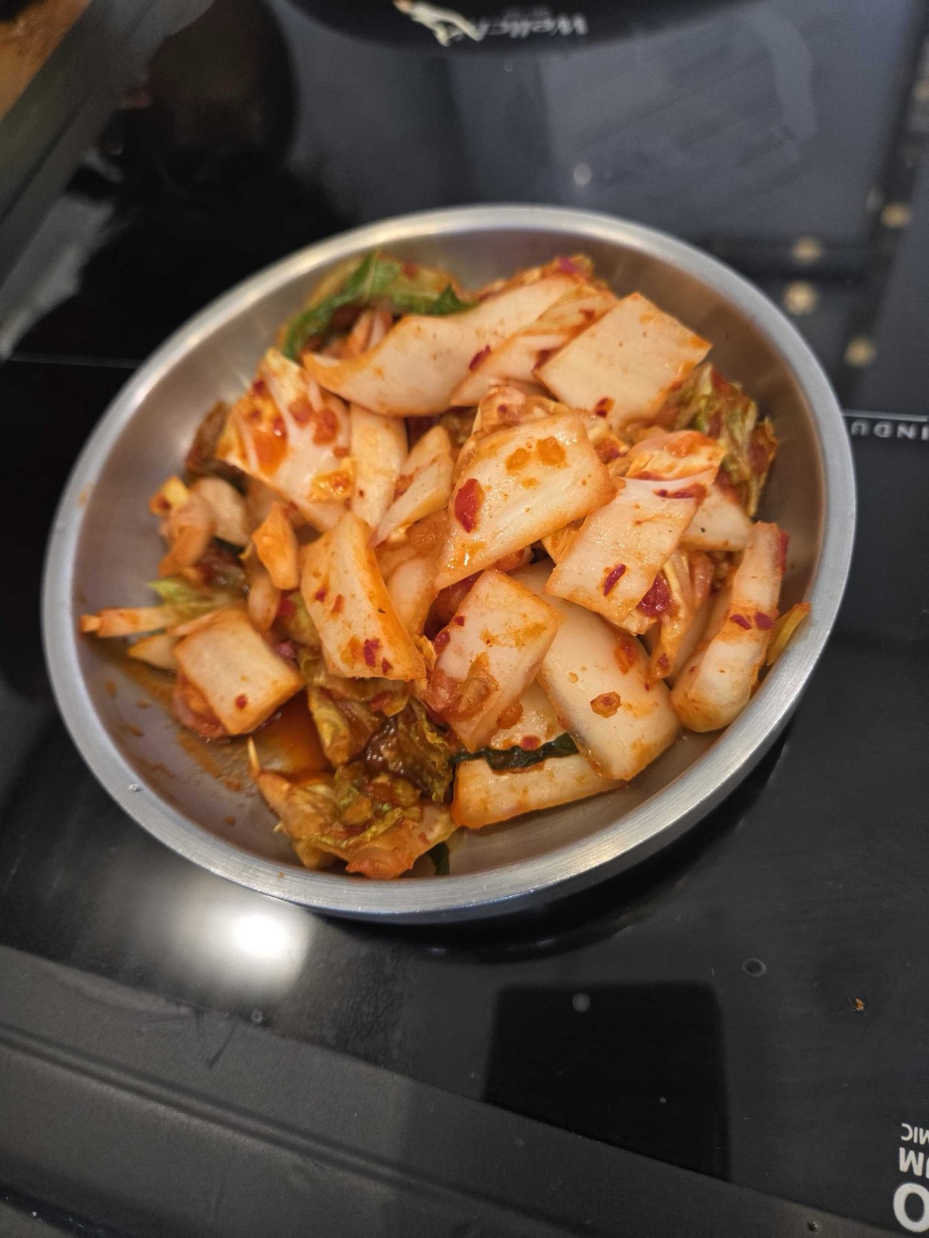 Bowl of fresh geotjeori kimchi on the induction table at Park Seung-gwang Haemul Kalguksu