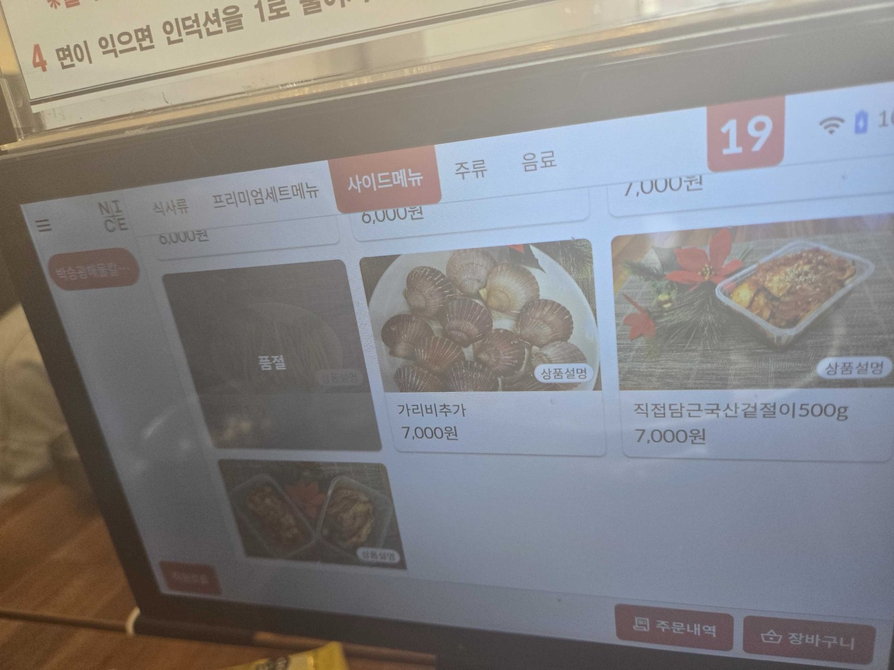 Scallop add-on and homemade geotjeori kimchi listed on the kiosk at Park Seung-gwang