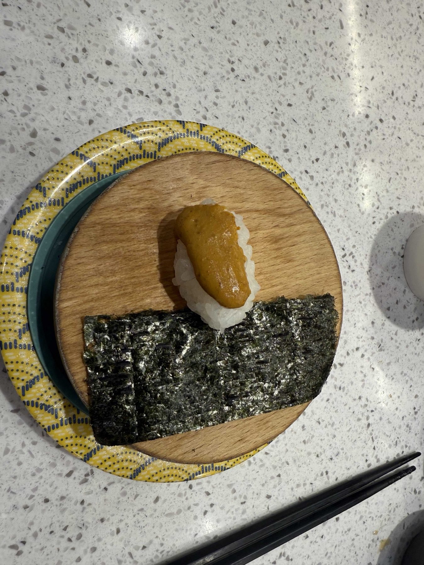 Roe-topped nigiri served with a strip of nori on a wooden round at Sushi Ian Wirye