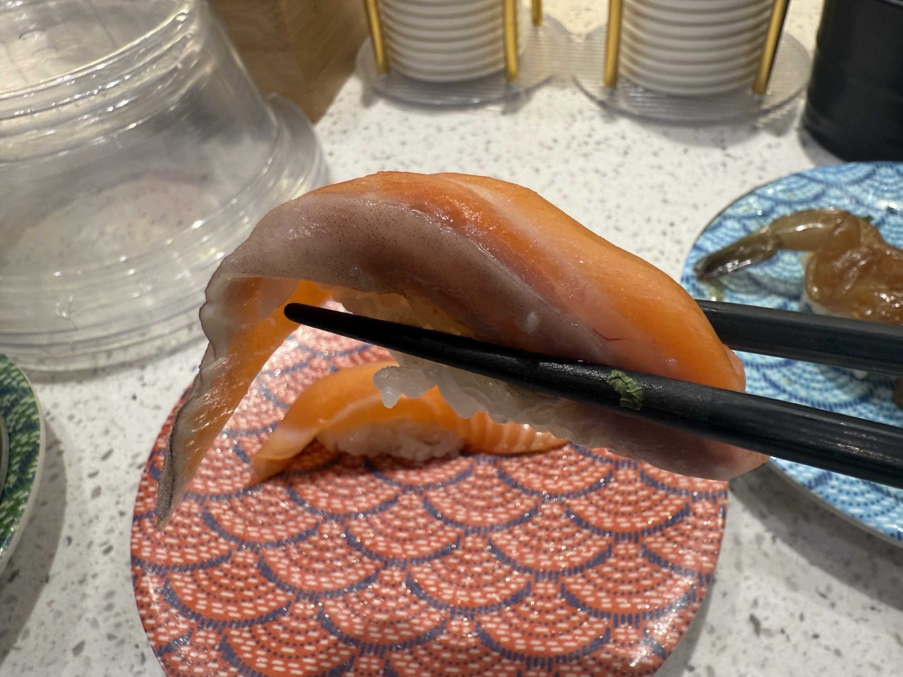 Salmon belly slice draped over black chopsticks at Sushi Ian Wirye