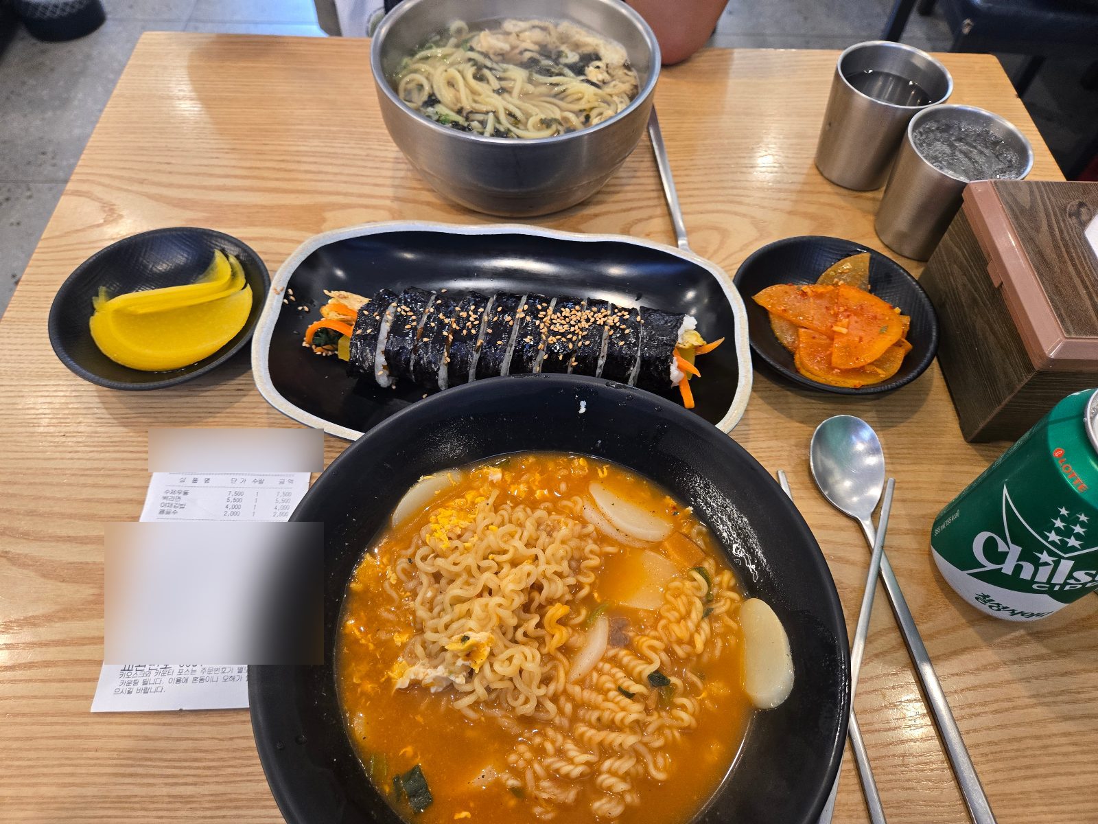 Handmade udon, tteok-ramyeon, vegetable kimbap, danmuji and radish kimchi on a wooden table