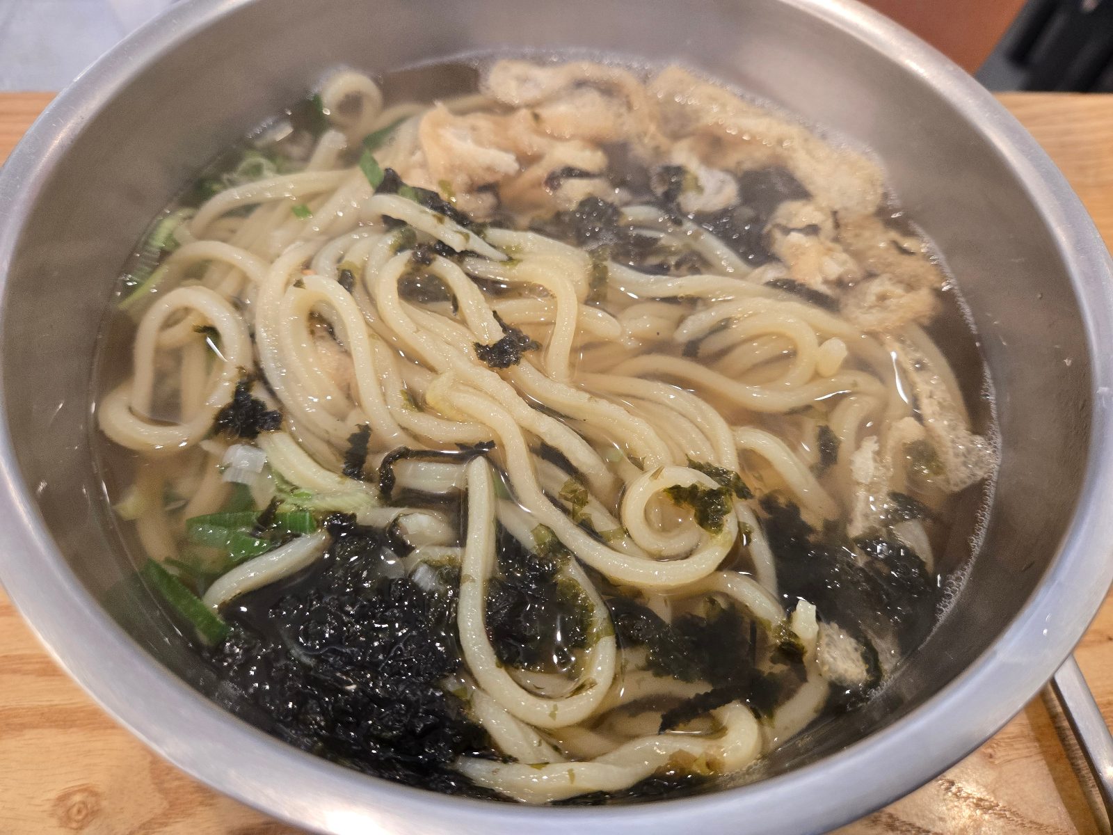 Thick udon noodles in clear broth with shredded seaweed and green onion