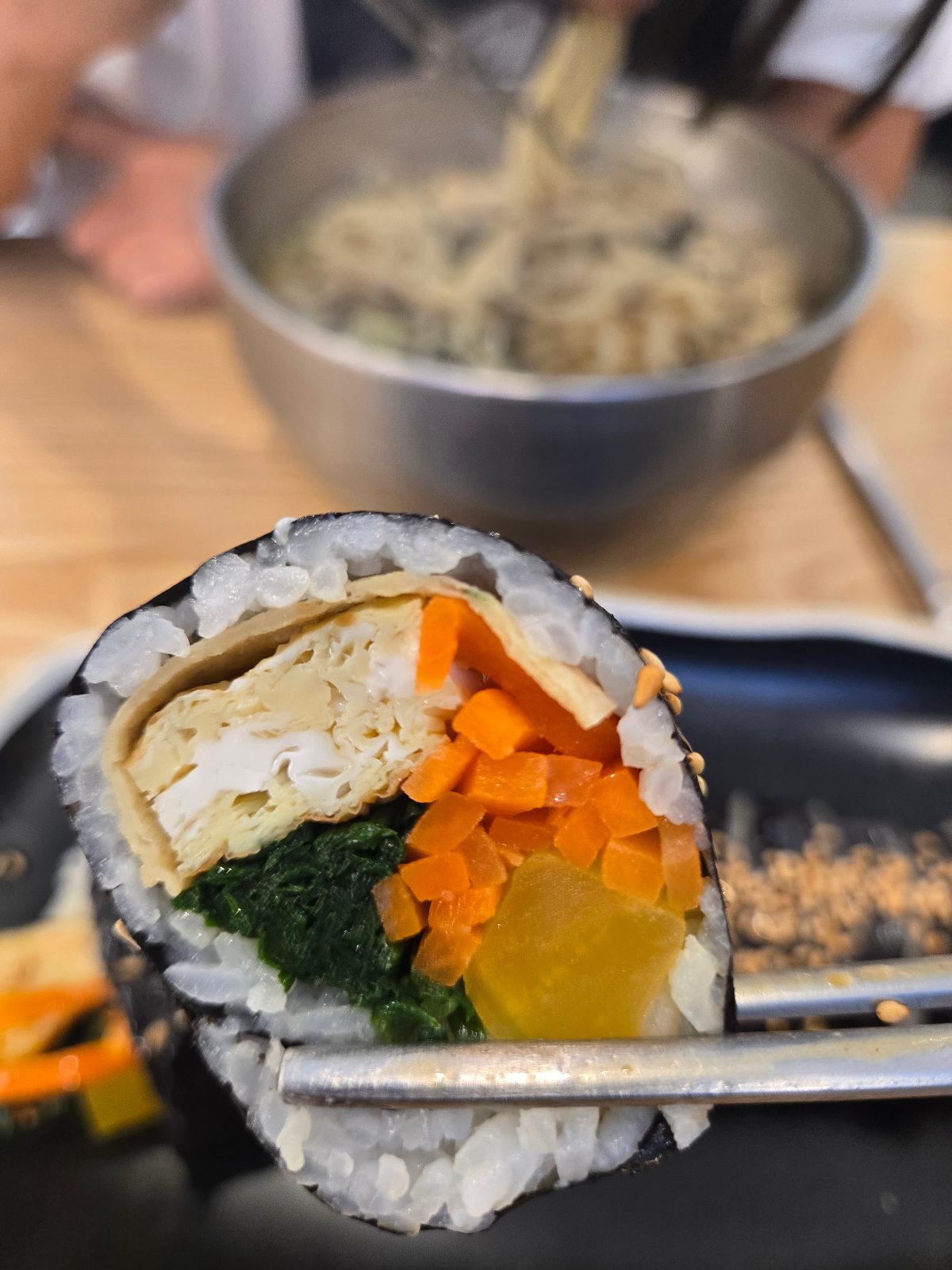 Cross-section of vegetable kimbap with egg, carrot, spinach and pickled radish
