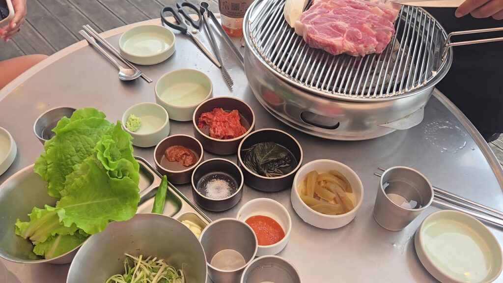 The table with the grill, lettuce and side dishes