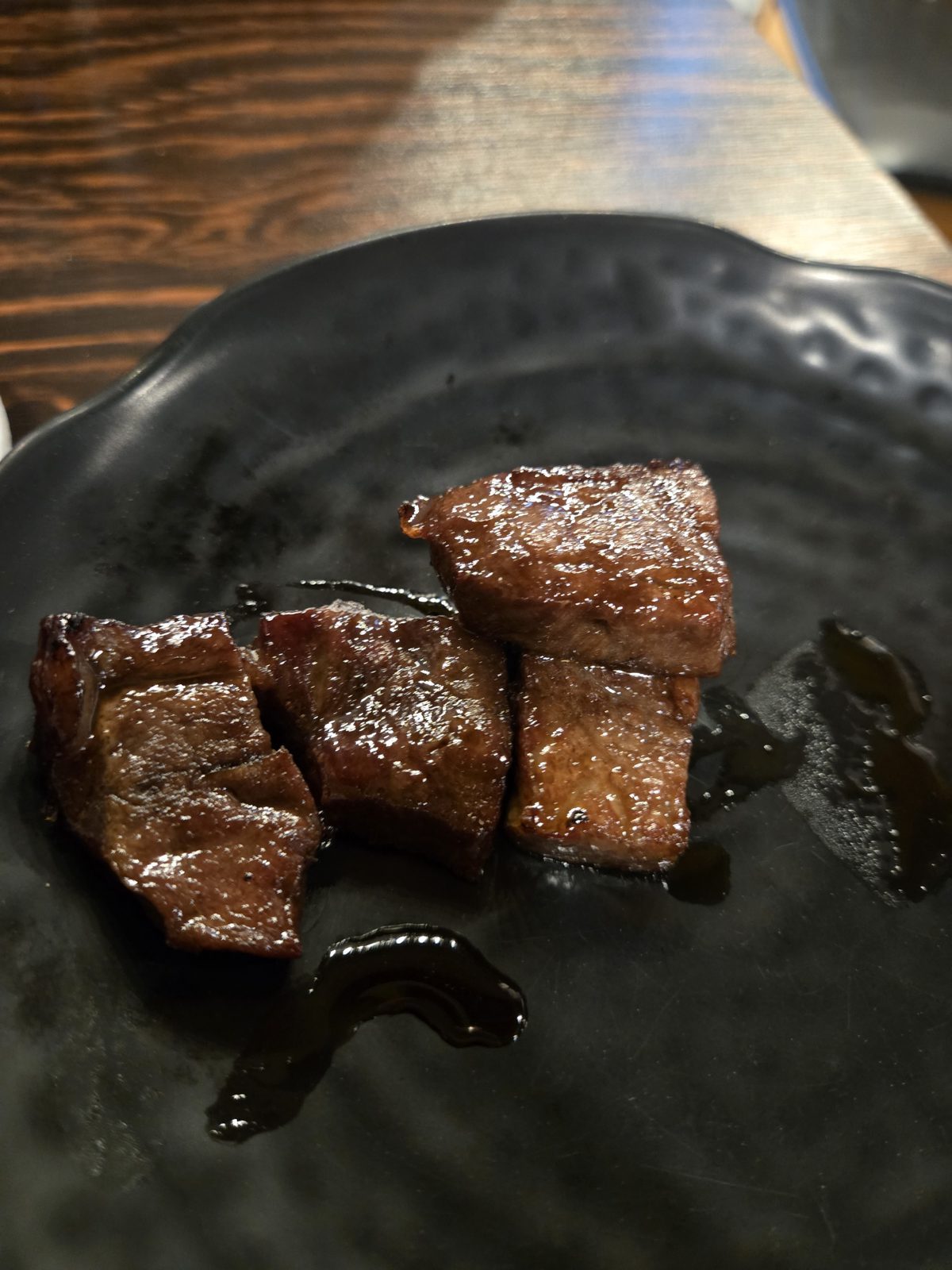Busaesal (beef flat iron) skewer pieces on a black plate